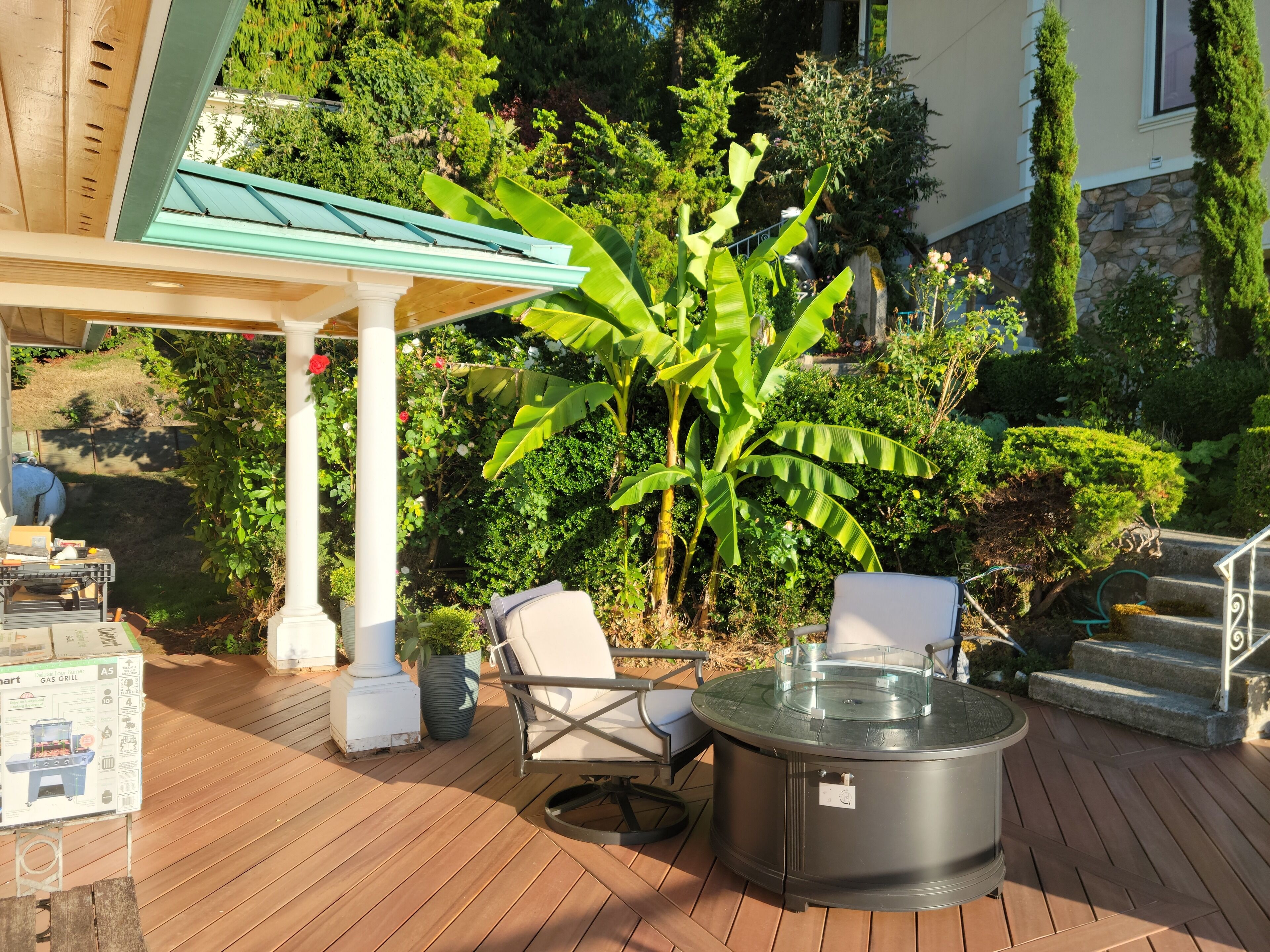 A patio with a gas grill, outdoor chairs, and a hot tub.