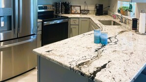 Une cuisine moderne dotée d’appareils électroménagers en acier inoxydable, de meubles de couleur claire et d’un plan de travail en granit.