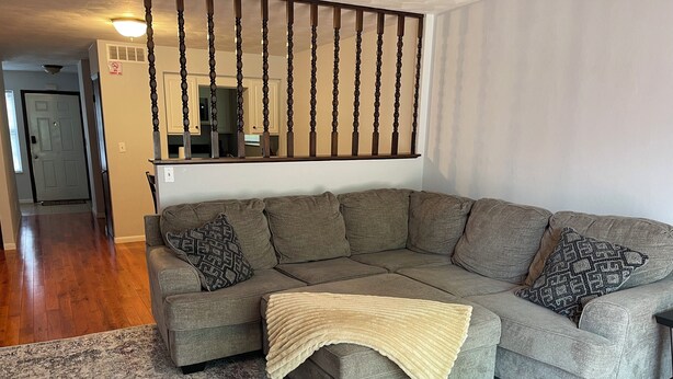 Un canapé modulable avec un plaid, un tapis à motifs et un escalier doté d’une balustrade.