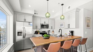 A modern kitchen with a central island, stainless steel appliances, and pendant lighting. - Luxury Condo w/ Beach Access | Dragestil 715-2 (Duluth)