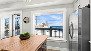 A kitchen with a wooden island, stainless steel refrigerator, and large windows overlooking a street. - Luxury Condo w/ Beach Access | Dragestil 715-2 (Duluth)