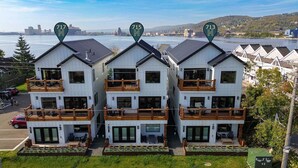 Et moderne hotel med toetagers bygninger, balkoner og udsigt over en flod og bybillede.