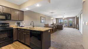 A modern kitchen with dark cabinets, a granite countertop, and a built-in dishwasher.