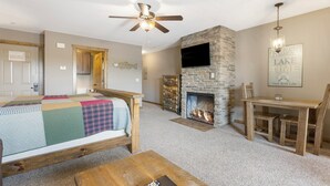 Una habitación acogedora con cama, chimenea, televisor y zona de comedor.