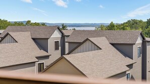 A residential area with multiple houses featuring gabled roofs and a view of a lake and distant hills. - Walk In Condo just 2 Min to SDC, Resort Perks, Lake Access, Ticket Deals! (Branson)