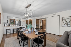 A modern kitchen with a dining area, featuring a wooden table, black chairs, and a pendant light. - 2 Lake-View Balconies | Updated 2BR/2BA | Less Than 5 Min to Silver Dollar City (Branson)