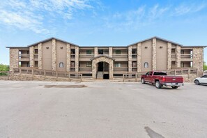 A multi-story building with a stone facade, balconies, and a central entrance.