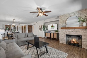 Ein Wohnzimmer mit Kamin, Deckenventilator und Essbereich.