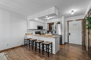A modern kitchen with white cabinets, stainless steel appliances, and a central island with bar stools.