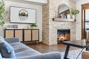 A living room with a stone fireplace, a sofa, a coffee table, and a framed picture on the wall.
