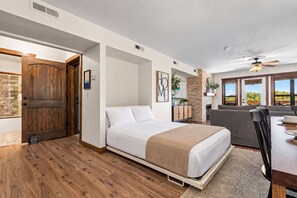 A hotel room with a bed, a seating area, a fireplace, and a view of the outdoors.