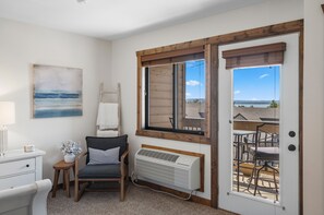 Une chambre avec vue sur la mer, une chaise, un radiateur et une table avec une lampe.