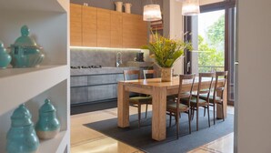Une cuisine moderne avec des meubles en bois, une table à manger avec des chaises et une plante en pot posée sur la table.