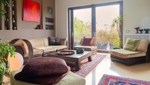 Un salon moderne comprenant un ensemble de canapés, une table basse et une grande porte-fenêtre coulissante donnant sur un jardin.