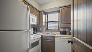 Una cocina compacta equipada con refrigerador, estufa, lavaplatos y pileta.