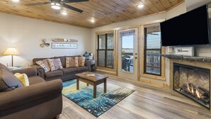 A living room with a brown sofa, a coffee table, a fireplace, and a television.