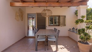 An outdoor patio with a wooden table and chairs, a potted plant, and a pergola overhead. - Holiday Home 'Ca N'Alicia Des Bosch' with Mountain Views, Private Terrace and Wi-Fi (Illes Balears)