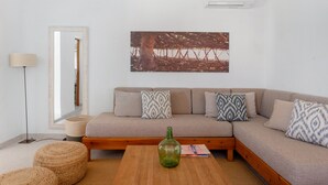 A living room with a sofa, ottomans, a coffee table, a lamp, and a framed picture on the wall. - Holiday Home 'Ca N'Alicia Des Bosch' with Mountain Views, Private Terrace and Wi-Fi (Illes Balears)