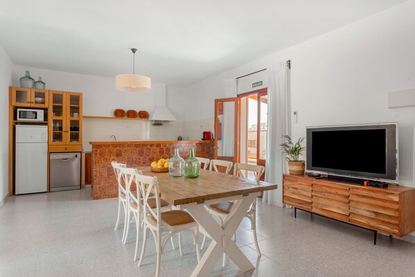 A modern kitchen with a dining area, a TV, and a view to the outside.