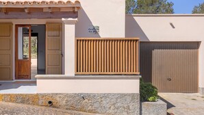 A building with a wooden door, a sign, a brown gate, and a stone wall. - Holiday Home 'Ca N'Alicia Des Bosch' with Mountain Views, Private Terrace and Wi-Fi (Illes Balears)