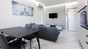 Un espacio habitable moderno con una mesa de comedor, sofá, televisor de pantalla plana y obras de arte.