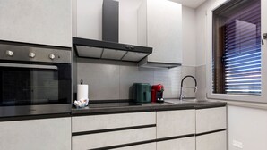 Una cocina moderna con horno empotrado, campana extractora de acero inoxidable y ventana con persianas.