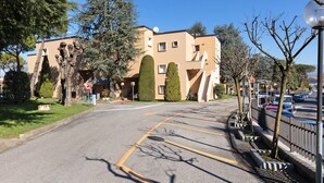 Una calle con un edificio de diseño moderno, un estacionamiento y una fila de árboles.