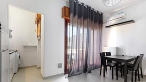 Una cocina moderna con lavadora, un comedor con mesa y sillas, y un amplio ventanal con cortinas.