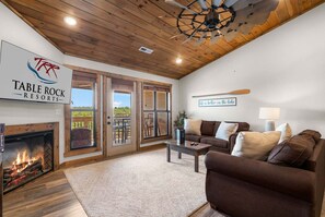 A cozy living room with a fireplace, a sofa, a coffee table, and a sign for Table Rock Resorts. - Morning Coffee with Lake Views Starts Here (Branson)