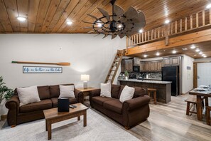 A cozy living room with a fireplace, a kitchen with wooden cabinets, and a loft area with a staircase. - Morning Coffee with Lake Views Starts Here (Branson)