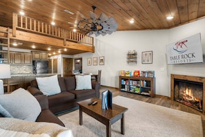A cozy living room with a fireplace, a bookshelf, and a dining area.