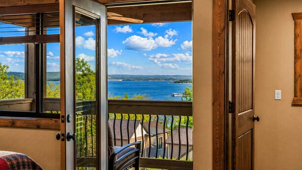 Ein Zimmer mit Holztür, Seeblick und einem Balkon mit Geländer.