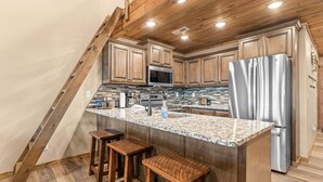 Eine Küche mit Holzausstattung, einem Edelstahlkühlschrank und einer Arbeitsplatte aus Granit.