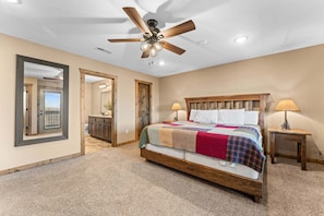 A bedroom with a large bed, a ceiling fan, two bedside lamps, and a view through an open door. - Lakeview Penthouse Near Silver Dollar City • Sleeps 13 • Boat Slip (Branson)