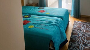 Huoneessa on kaksi sänkyä, kattovalaisin, näkymä ulos ja kuviollinen matto.