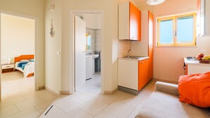 Une chambre d’hôtel de taille réduite, dotée d’une kitchenette, d’une salle de bain et offrant une vue sur l’extérieur.