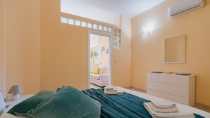 A bedroom with a bed, pillows, a dresser, an air conditioner, and a window. - Holiday Home 'Anthea in Otranto' with Balcony, Wi-Fi, and Air Conditioning (Otranto)