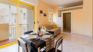 A dining area with a table set for four, a sofa, and a balcony with yellow railings. - Holiday Home 'Anthea in Otranto' with Balcony, Wi-Fi, and Air Conditioning (Otranto)