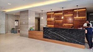A modern reception desk with a marble top and wooden panel backdrop.