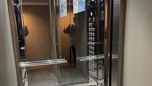 An elevator with a mirrored wall and a tiled floor.