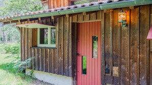 Une cabane en bois avec une porte rouge, une fenêtre et une lanterne.