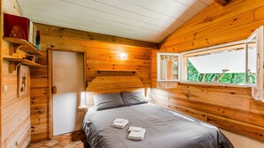 Une pièce dans une cabane en bois, comprenant un lit, une fenêtre et une porte.