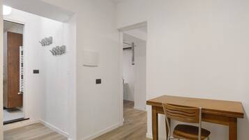 A hallway with a wooden door, a coat rack, and a table with a chair.
