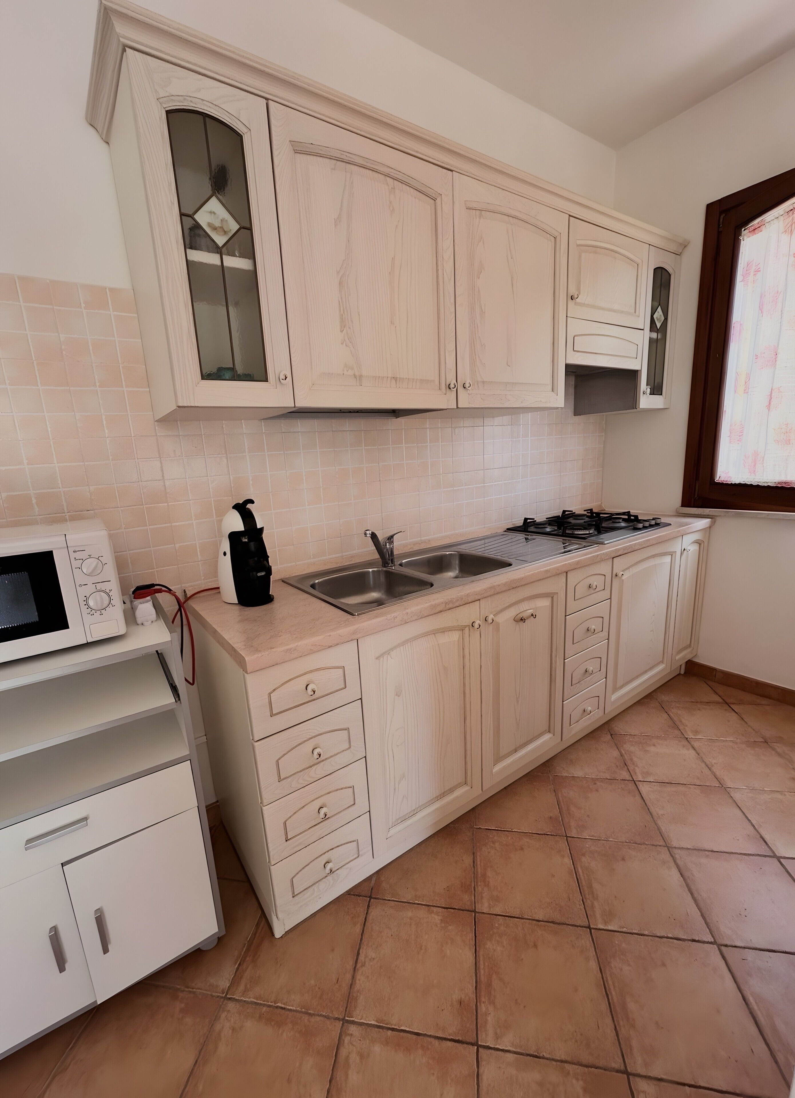 A kitchen with white cabinets, a microwave, a gas stove, and a sink.