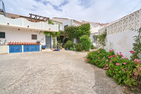 A courtyard with a concrete floor, a blue gate, and a white wall with a geometric pattern.