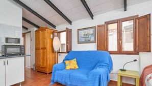 Una stanza con angolo cottura, un divano blu, un armadio in legno e un quadro appeso al muro.