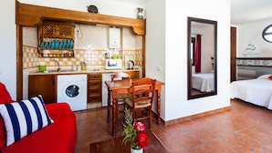 Un espacio habitable compacto con kitchenette, lavadora, comedor y cama.