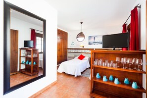 Una camera d'albergo con un letto, una televisione, una libreria e uno specchio.