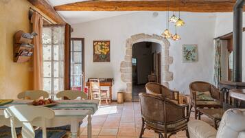 A rustic interior with a dining area, wicker furniture, stone archway, and a fireplace.