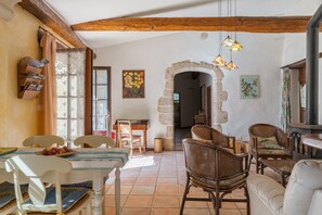 Un interior rústico con comedor, mobiliario de mimbre, un arco de piedra y chimenea.